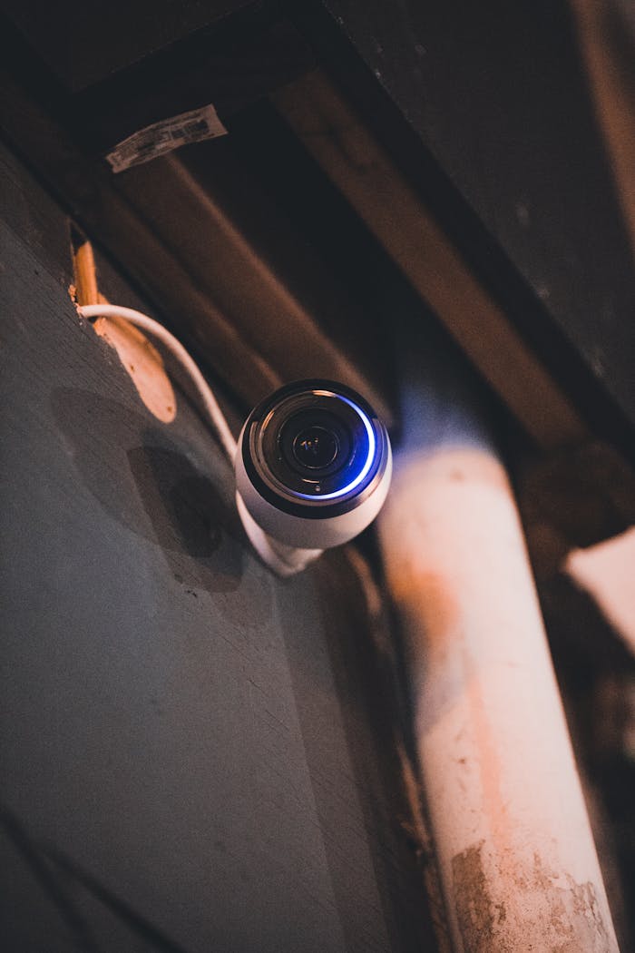 A security camera mounted on an indoor wall with ambient lighting.